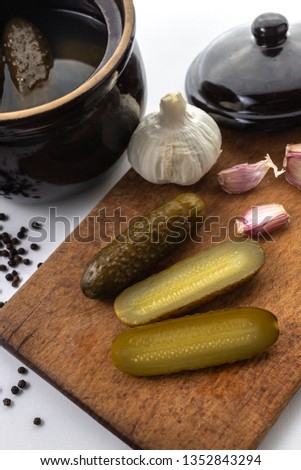Pickled cucumbers, pepper, garlic, and a stone pot. Sliced cucumbers on a wooden board.. White background. Pictures of vegetables for the website. Polish cuisine. 