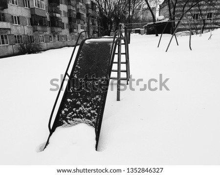 Childrens playground near the house in winter in the snow