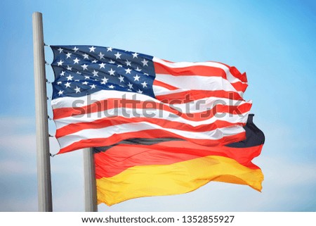 Flags of the USA and Germany against the background of the blue sky