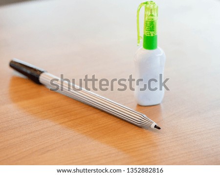 Selective focus pen with liquid paper on wooden desk.