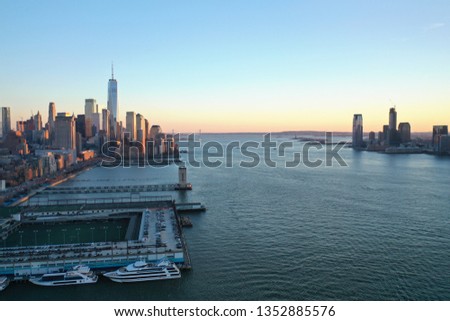 Photo shows New York Manhattan and New Jersey skyline. The 2 sides of cities are divided by river. Manhattan is with a lot of high rise building while New Jersey is not. Photo taken during sunset hour