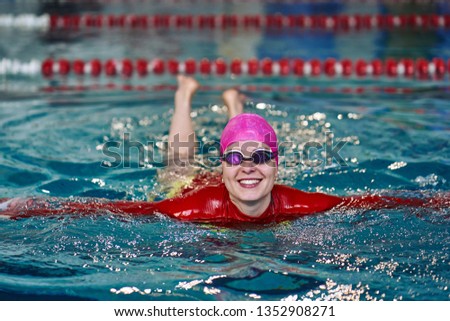Portrait of a smiling woman swimmer in red yellow swimsuit in the pool after the completion of training.