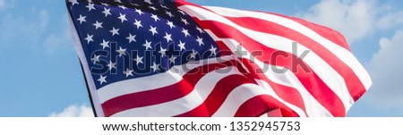 panoramic shot of american flag with stars and stripes against blue sky