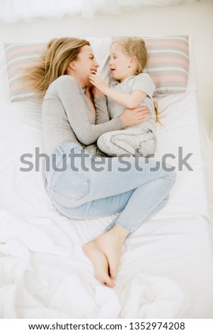 Young mother and her little daughter at home at sunny morning. Soft pastel colors. Happy family time on weekend. Mother's Day concept. Family, love, lifestyle, motherhood and tender moments concepts.