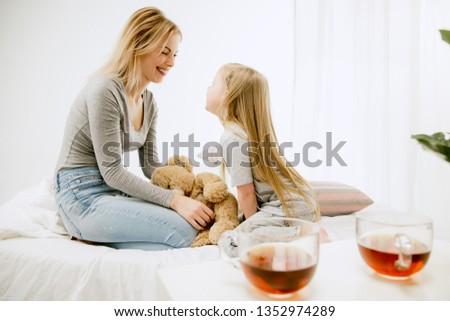 Young mother and her little daughter at home at sunny morning. Soft pastel colors. Happy family time on weekend. Mother's Day concept. Family, love, lifestyle, motherhood and tender moments concepts.