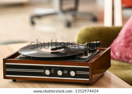 Record player with vinyl disc on table in room Royalty-Free Stock Photo #1352974424