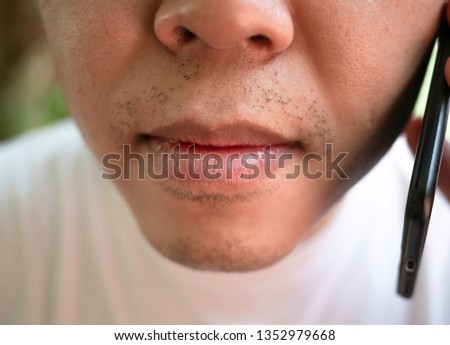 Close-up mouth picture of Asian men with using smart phone and wearing a white shirt.