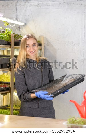 Portrait of blonde girl in a home mini farm plants micro greens home business, modern greenhouse