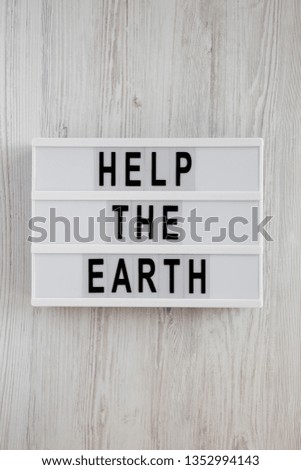 'Help the Earth' words on modern board over white wooden background, top view. Flat lay, overhead, from above.