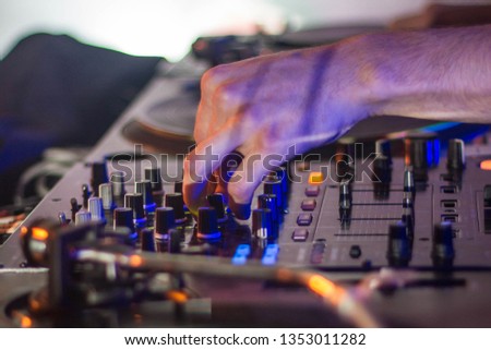 Detail of DJ's hand adjusting knobs on a dj mixer