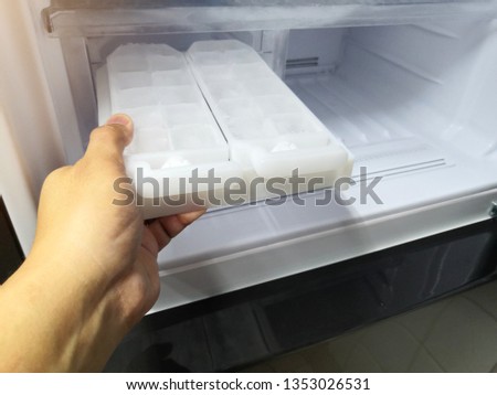 Man hand holding ice maker in new refrigerator.Closed up.