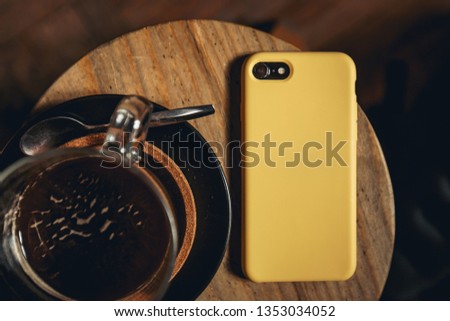 Yellow smartphone case on a table next to coffee.