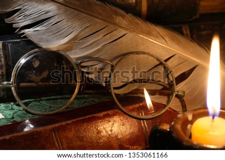 Vintage still life with old glasses against lighting candle and books