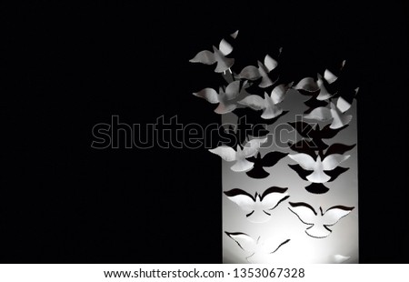 White doves flying away into the dark from a white stand - a beautiful postcard with negative space.