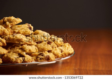 Stack of cookies on a metal cooling grid placed on a wooden surface with black background 