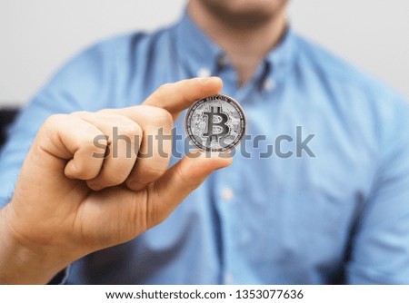 Man holding silver physical bitcoin. Symbol of virtual currency.