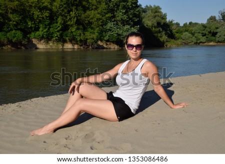 The girl in a white T-shirt on the sandy bank of the river.  beautiful girl on the river beach.