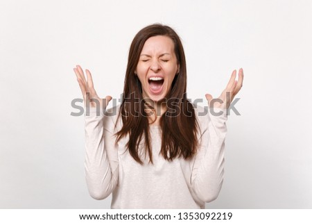 Portrait of crazy screaming young woman in light clothes keeping eyes closed spreading hands isolated on white wall background in studio. People sincere emotions lifestyle concept. Mock up copy space