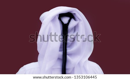 Portrait of an unknown Qatari man from behind in a traditional uniform isolated on maroon background Royalty-Free Stock Photo #1353106445