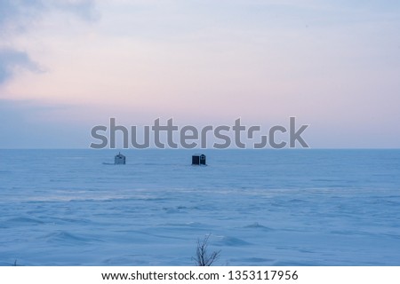 ice fishing huts on lake in early morning light in winter