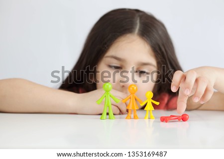 Happy traditional family figurines. A small child plays with colored plastic figures. Mom, dad, brother, sister, siblings. Family symbol. Adoption. Full family. Face out of focus. 