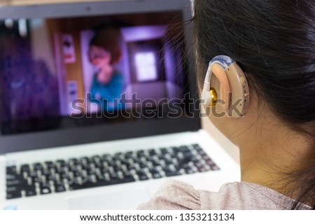 Asian children watch cartoons using hearing aids.
