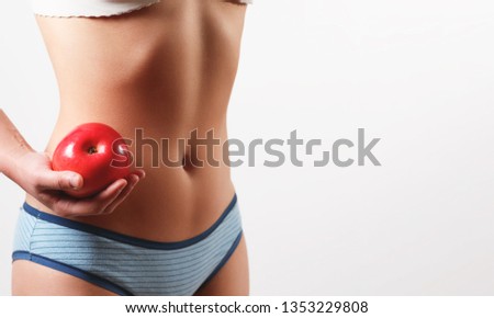 close up photo. slender slim figure waist belly young woman girl. Holding a juicy red Apple on white background