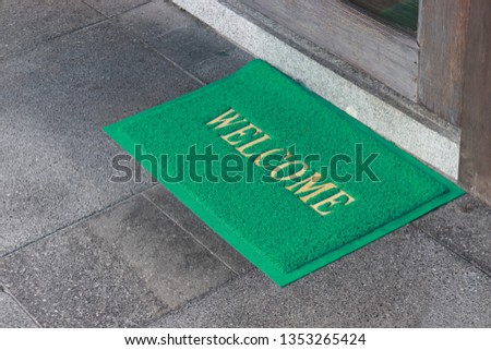 welcome text on green doormat in front of door