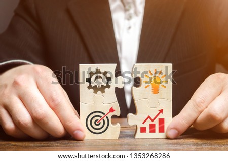 Businessman collects puzzles with the image of the attributes of doing business. Strategy planning concept. Organization of the process. Creating a business model. Management. Research, marketing. Royalty-Free Stock Photo #1353268286