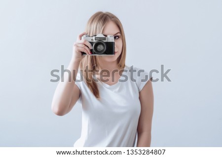 Attractive girl holding vintage camera in her hands. Take a picture.