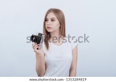 Attractive girl holding vintage camera in her hands. Looking away