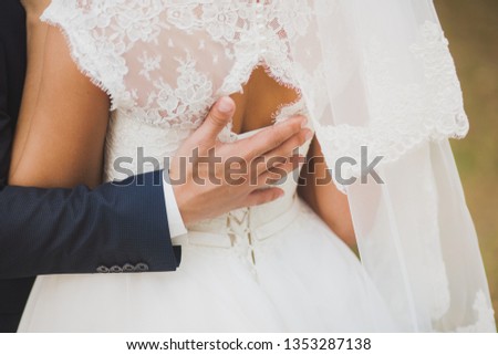 Groom embracing his wife with passion and love. Horizontal color photography of wedding couple.