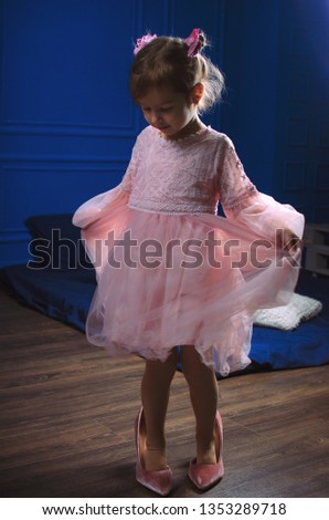 Little girl in pink dress photoshoot in the Studio. dancing in shoes is not the size. large shoes, heels, maximalism, it is not convenient to dance