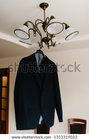 A man's jacket on a hanger on the background room.