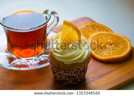a glass cup of tea, a cupcake with orange slices on a wooden tray. Healthy food. tea party