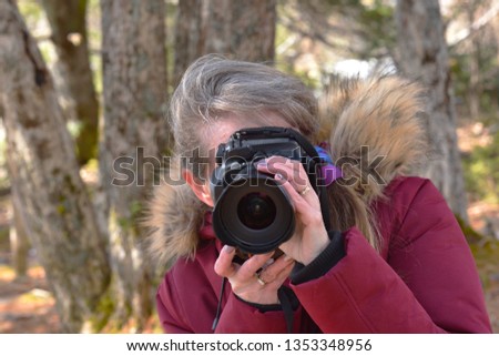 Middle Age Woman in Red Coat Taking Pictures in a Park in Winter
