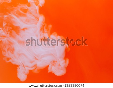 White acrylic paints inside water on the orange and red background. Watercolor style and abstract spring or summer image of fire.