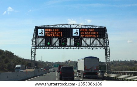 big electronic road sign with text that means Winter Equipment Obligation in italian language and the police symbol in the motorway in Italy