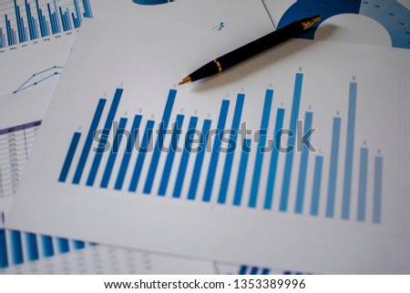 Many charts and graphs with magnifying glass and many pencil. Reflection light and flare. Concept image of data gathering and statistical working. Royalty-Free Stock Photo #1353389996