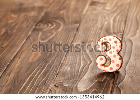 number three on a wooden background. gingerbread with frosting.