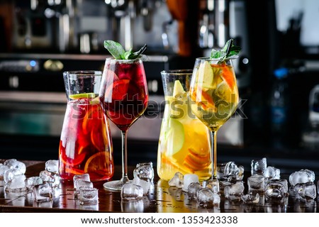 White and red sangria with fruit and ice. Summer alcohol drink and ingredients. sangria with red and white wine in decanter with wineglasses in wine glass on bar blurred background