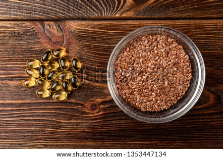 Fish oil and flax seeds on dark wooden background.