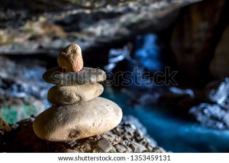 Beautiful unusual cave with a waterfall and a pyramid of stones. Dark natural cave with a ray of light for solitude and relaxation in nature. Copy space