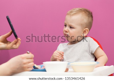 Cute little boy, eats breakfast at home, while watching cartoon on tablet. Portrait of the little boy eating Mashed potatoes