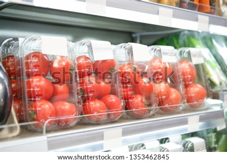 Fresh red tomato vegetables in transparent plastic boxes at organic foods aisle in supermarket. Delicious natural tomatoes in containers selling at food store. Buy good healthy ingredients for meal