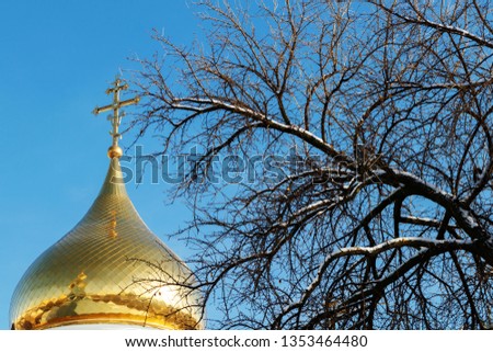 Eastern orthodox cross on gold dome againts blue sky in sunny day. 