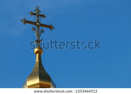 Eastern orthodox cross on gold dome 
 againts blue sky in sunny day. 