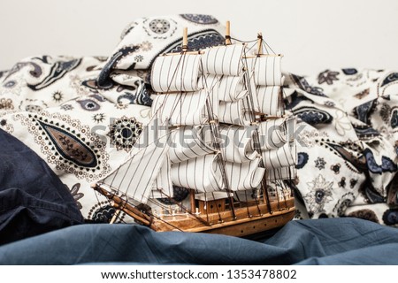 Concepts of business and creativity. model of a sailing ship in a bed with a carelessly crumpled blanket and pillows in blue bedding. Close up