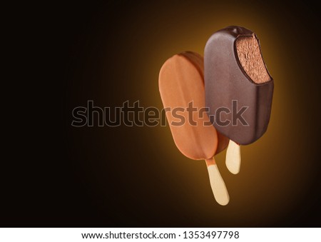 Two Bitten chocolate ice cream popsicles with dew on brown to black gradient background