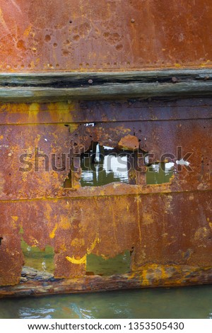 Gaping hole in a portion of scuttled rusting hulk of old ship Waverley in shallows of Wairau Lagoons on nature walk. Royalty-Free Stock Photo #1353505430
